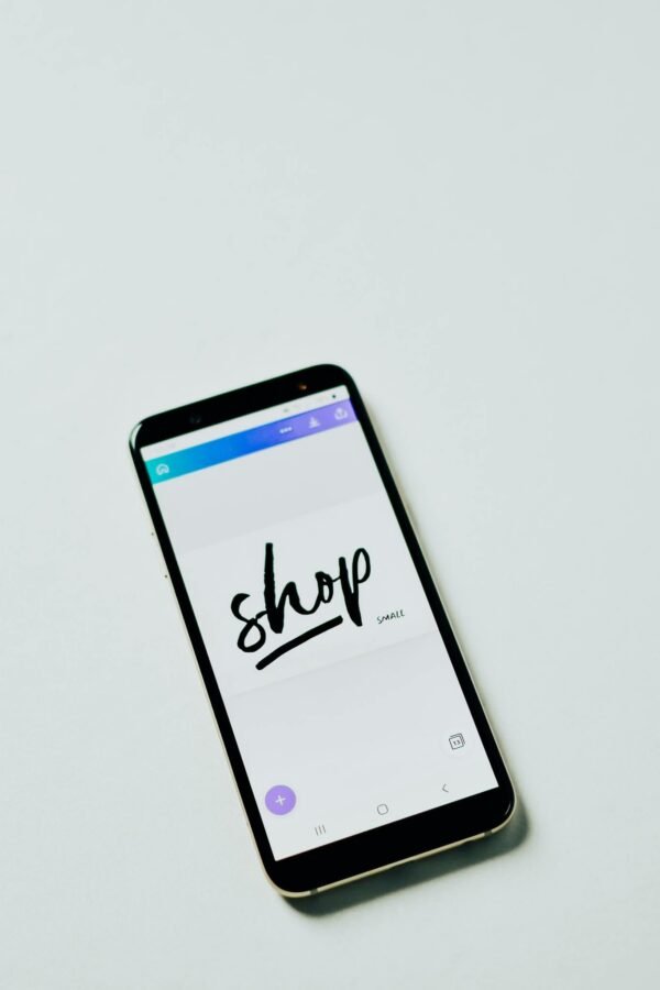 A close-up shot of a smartphone with a shopping app on a white surface, ideal for e-commerce themes.